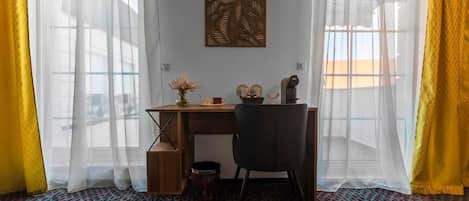 A room with a desk, chair, and a decorative wall piece.