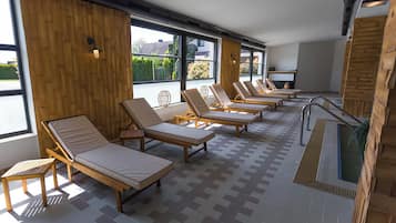 Una sala de estar con mucha luz natural, varios sillones cómodos dispuestos en filas, ventanas amplias y suelo de baldosas.