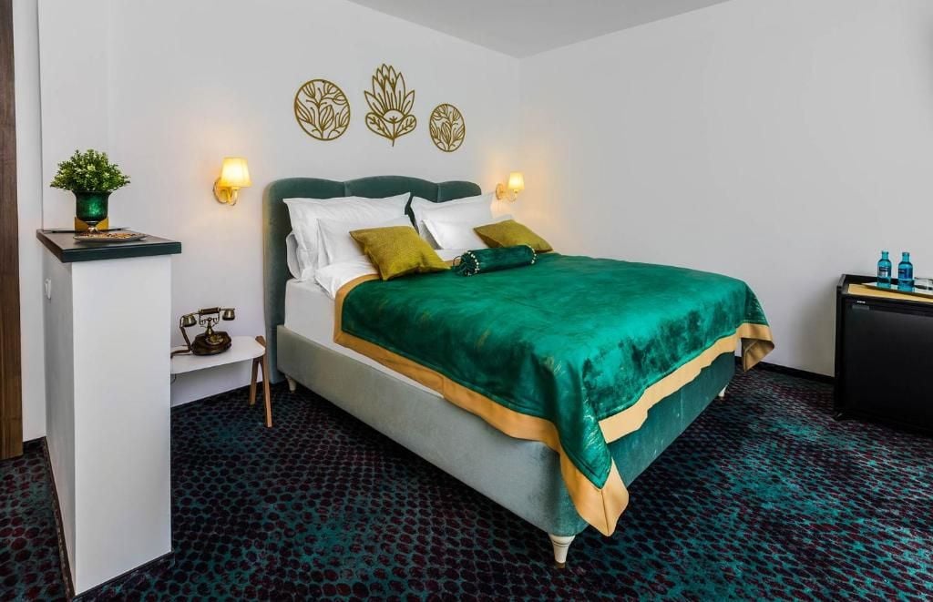 Ein Hotelzimmer mit Bett, Nachttisch, Lampe, Wanddekoration und einer kleinen Pflanze.