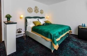 Ein Hotelzimmer mit Bett, Nachttisch, Lampe, Wanddekoration und einer kleinen Pflanze.