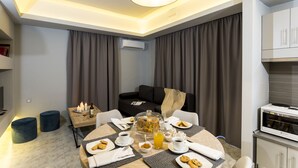 Une chambre d’hôtel moderne dotée d’un coin repas, d’un canapé et d’une kitchenette.