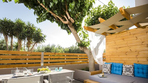 Une terrasse extérieure avec une table, des chaises et un banc en bois.