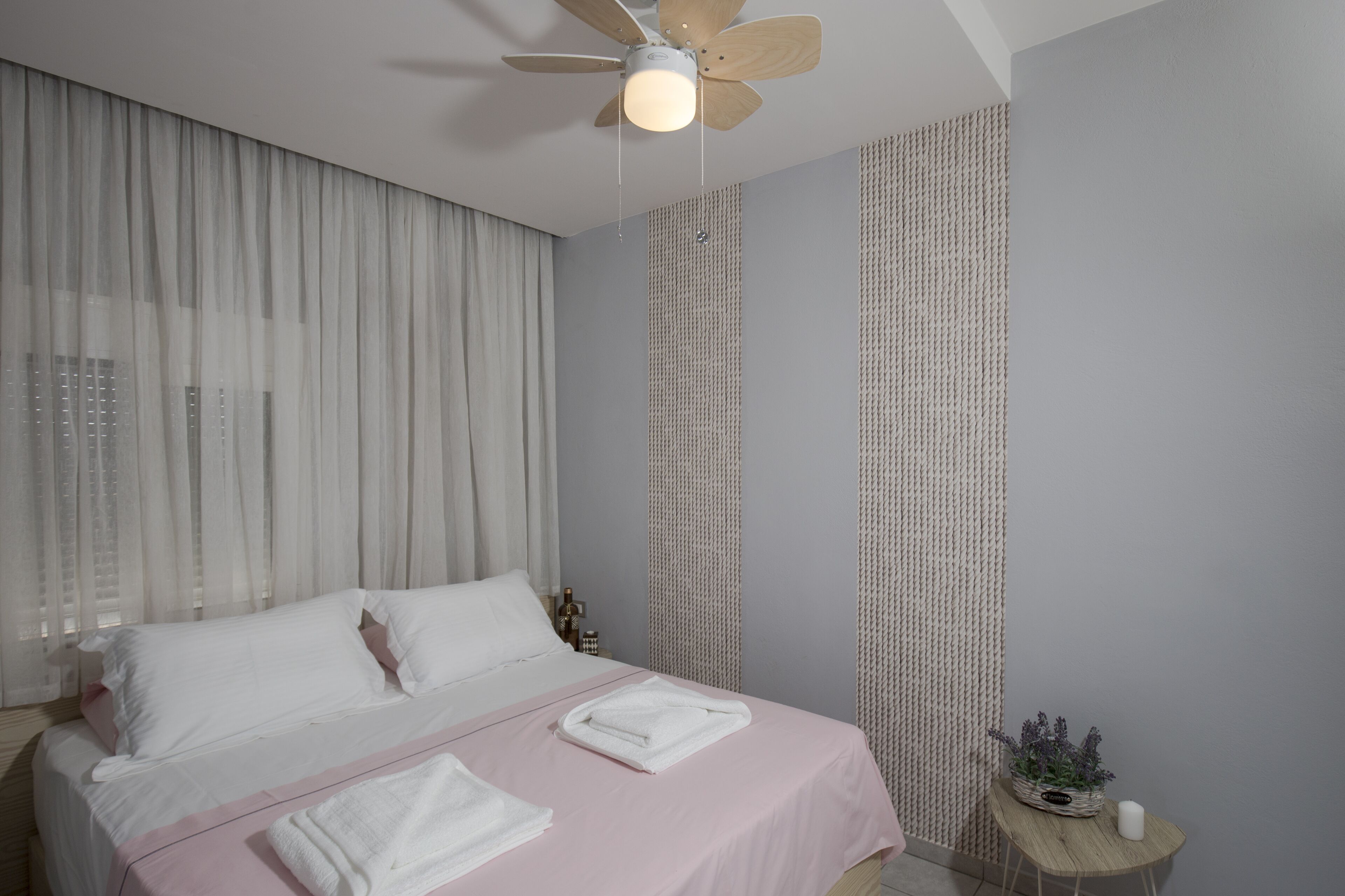 A modern bedroom with a bed, a ceiling fan, and a small bedside table with a plant.