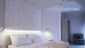 Une chambre d’hôtel moderne avec un grand lit, une table de chevet, une lampe de lecture et un petit coin salon.