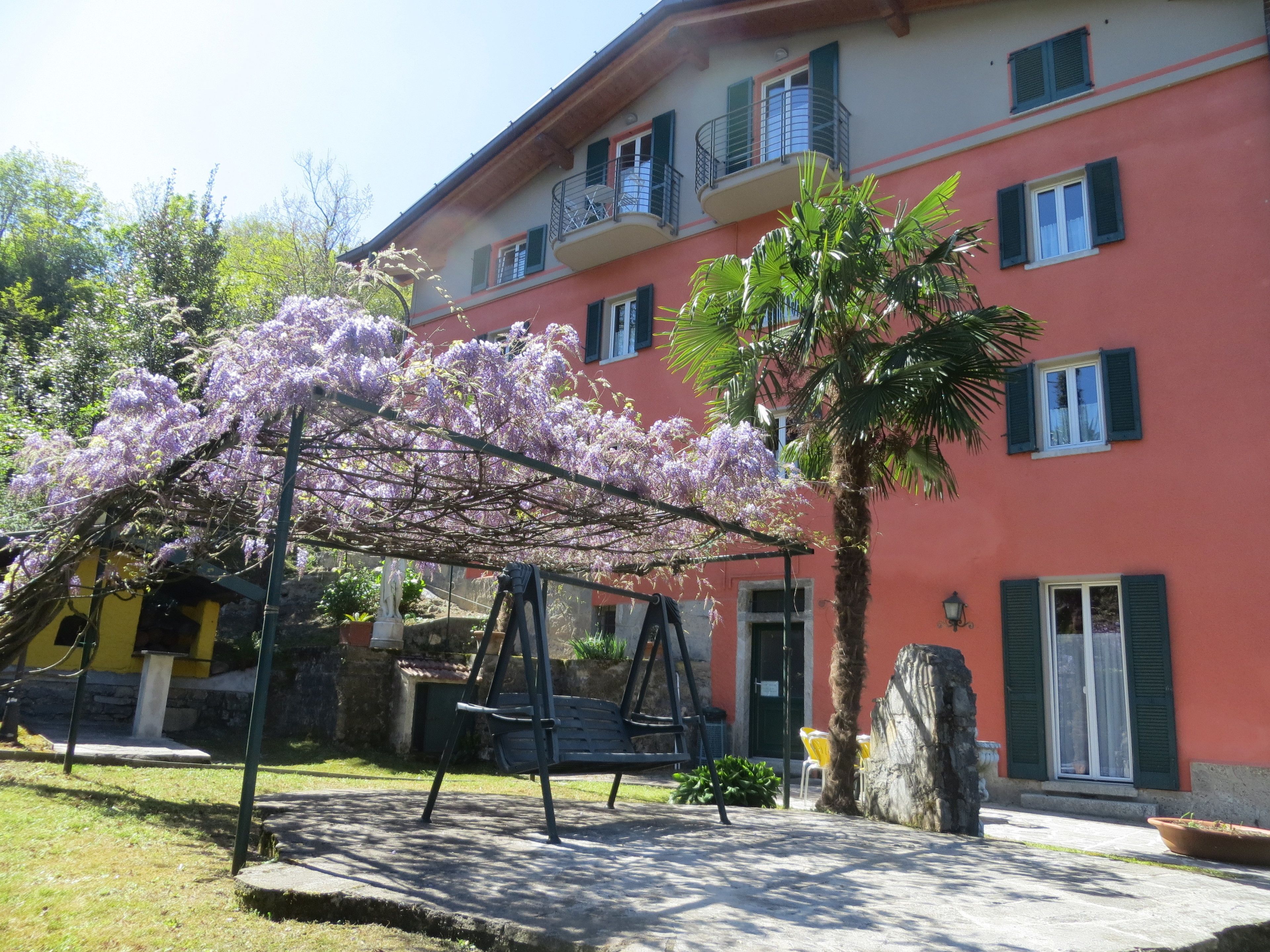 A building with a red facade, balconies, and a swing set in front.