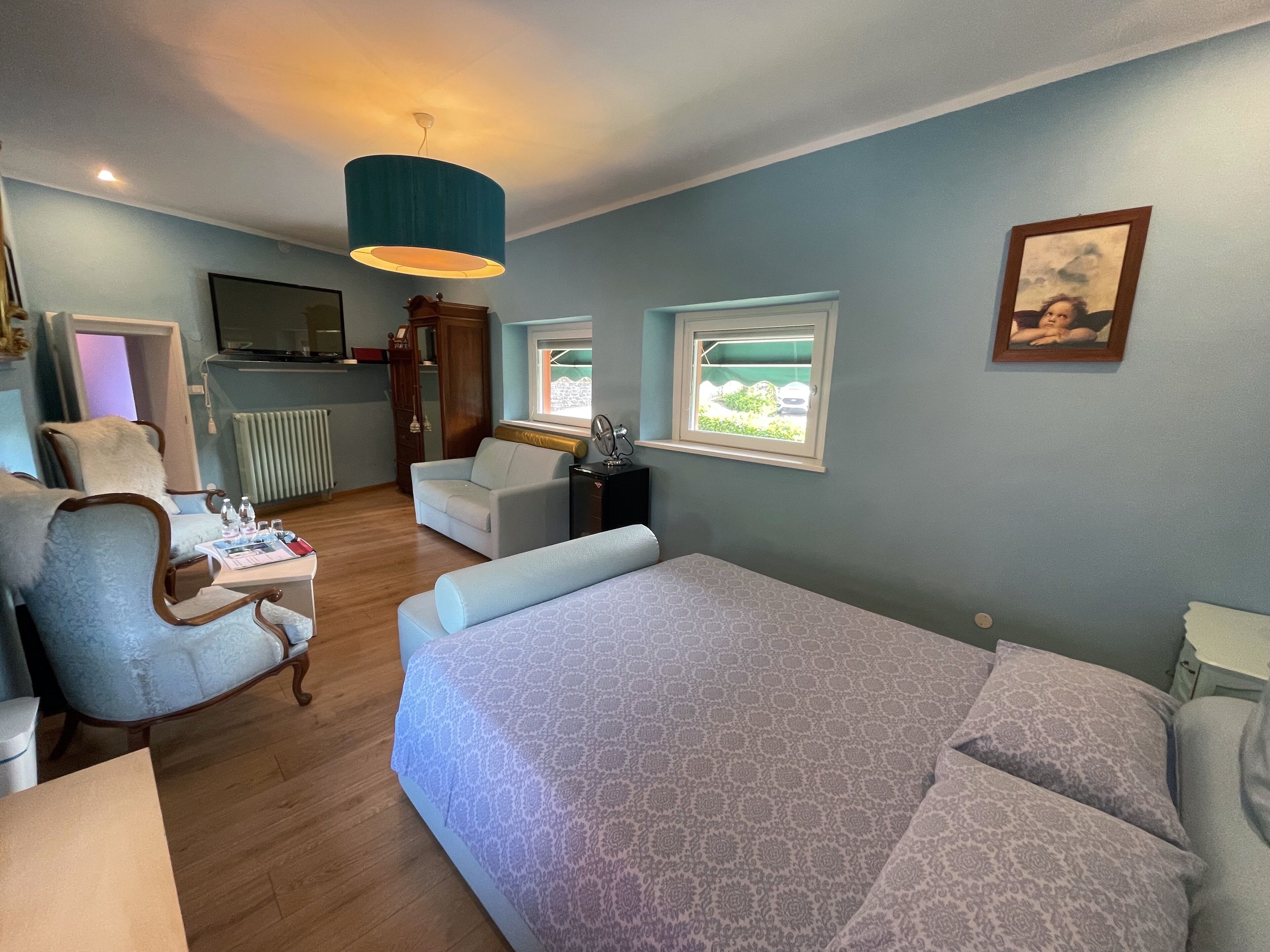 Ein Schlafzimmer mit einem Bett, zwei Stühlen, einem Schreibtisch, einer Kommode und einem Fenster.