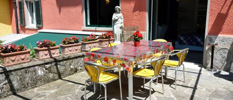 An outdoor patio with a table and chairs, a statue, and flower planters.