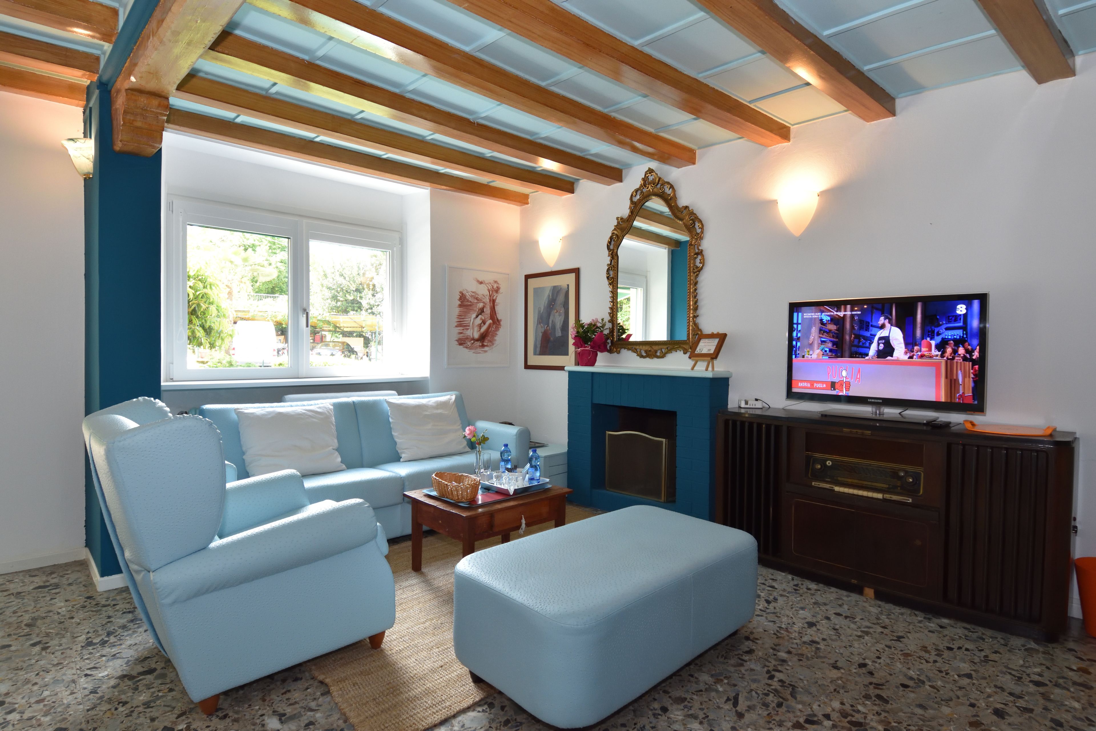 A living room with a blue sofa, a wooden coffee table, a television, and a fireplace.