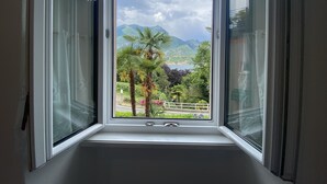 A window with a view of mountains, palm trees, and a lake. - Bellagio Bed & Breakfast (Bellagio)