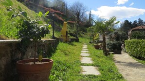 A garden pathway with a yellow sculpture, potted plants, and a stone wall. - Bellagio Bed & Breakfast (Bellagio)