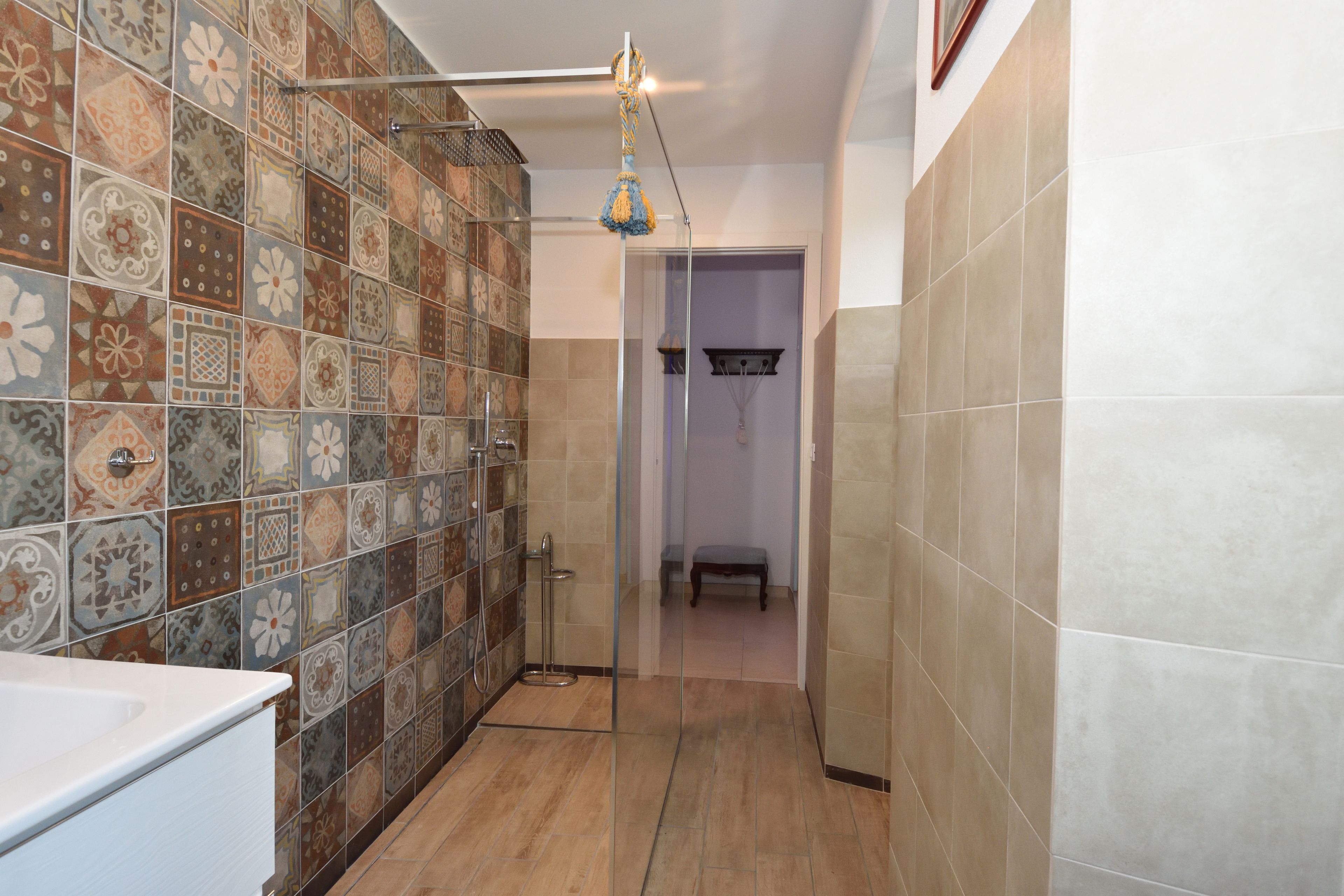 A bathroom with patterned tiles, a shower area, and a bench.