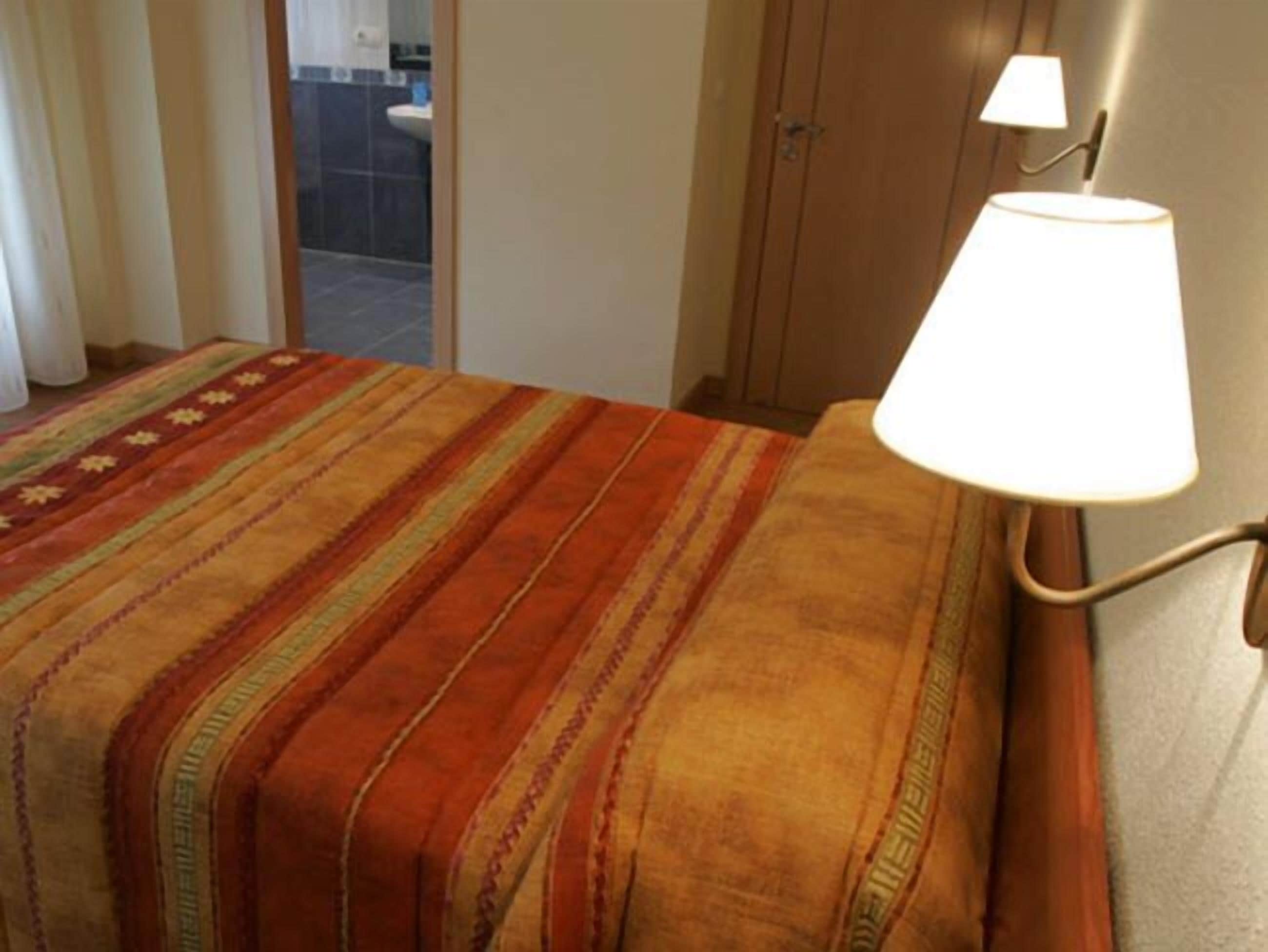 Un letto con una coperta a righe e una lampada da comodino.