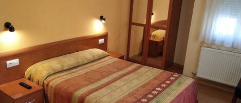 Un dormitorio con cama, mesitas de noche, armario y radiador.