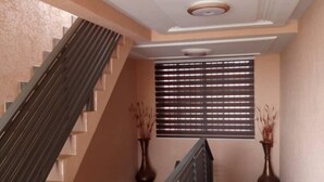 A staircase with a handrail, a window with blinds, and a ceiling with recessed lighting. - Alpha's Court (Kumasi)