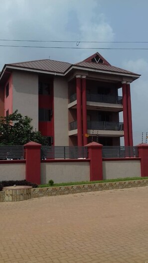 A multi-story building with a flat roof, balconies, and a paved entrance area. - Alpha's Court (Kumasi)