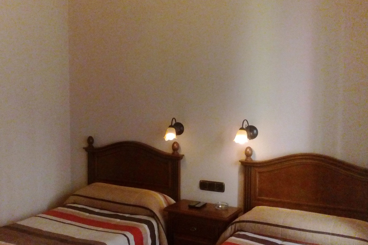 Ein Schlafzimmer mit zwei Einzelbetten, einem Nachttisch mit Lampe und einem Spiegel an der Wand.