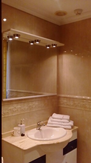 A bathroom with a sink, mirror, and towel rack. - Hostal Granada (Salamanca)