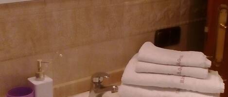 A bathroom with a sink, a mirror, a towel rack, and a purple mug.