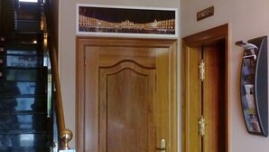 Un'imponente porta in legno con decorazioni nella parte superiore, una scala con gradini scuri e un televisore montato a parete.
