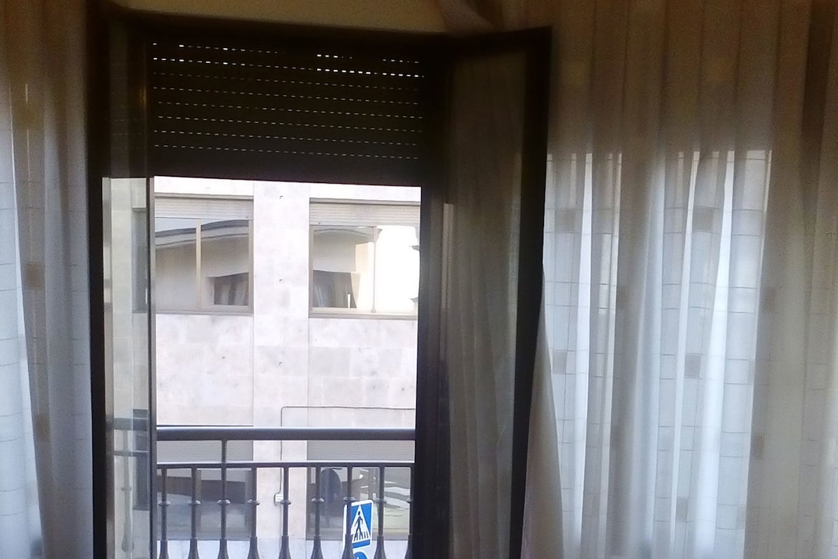 Ein Hotelzimmer mit zwei Betten, einem Balkon mit Blick auf das Gebäude und einem Schild, das einen Fußweg anzeigt.