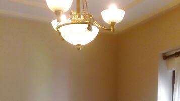 A hotel room with a wooden bed, a nightstand, a lamp, and a chandelier.