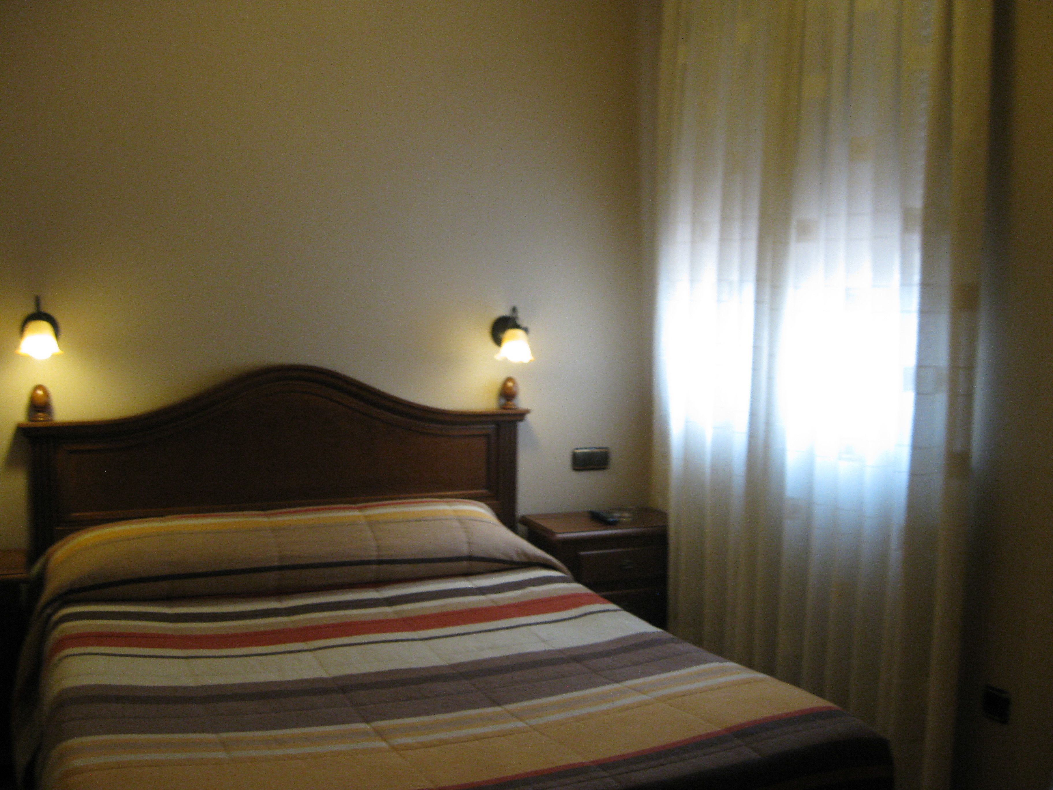Una cama con un edredón a rayas, dos lámparas de noche y una mesita de noche.