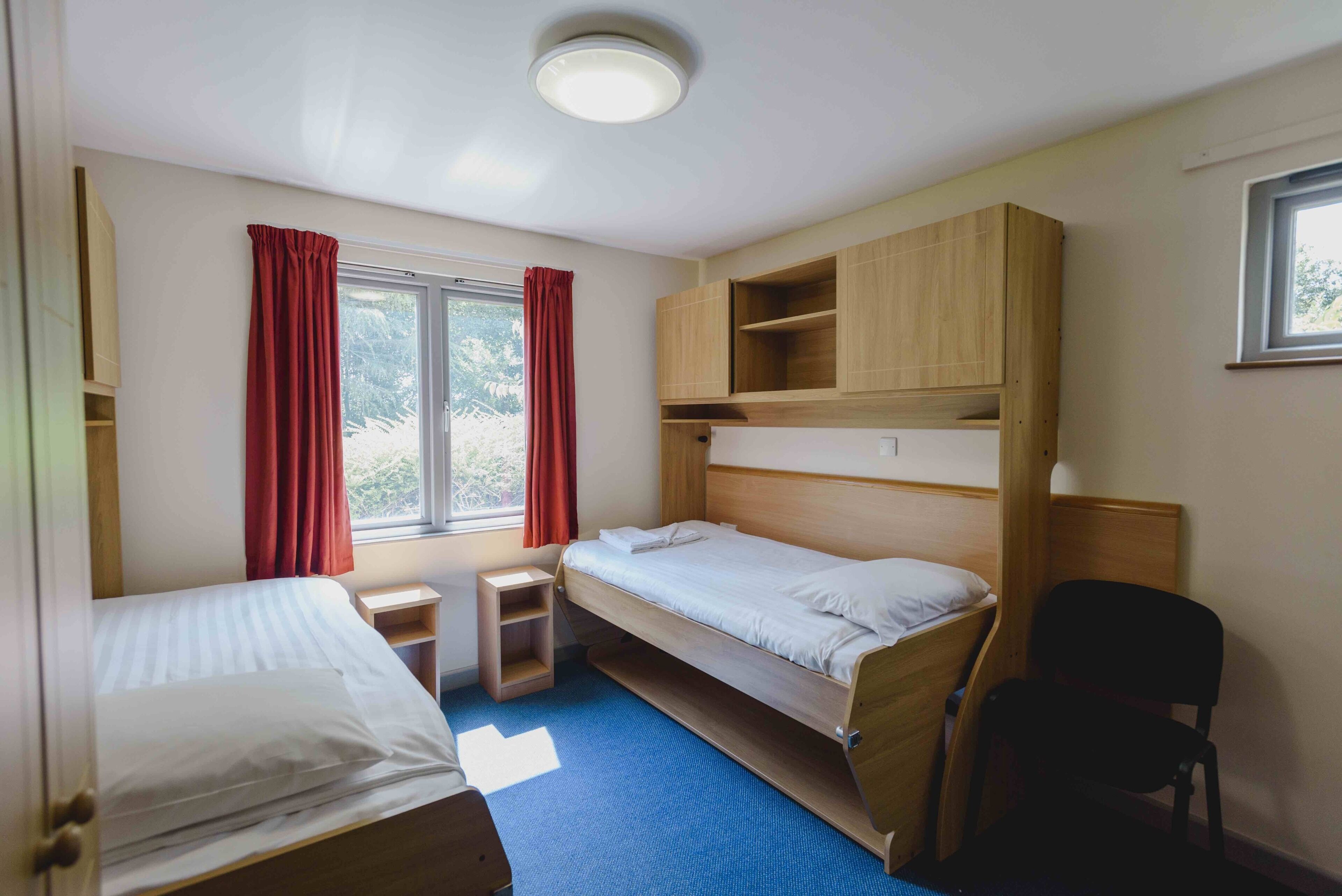 A compact room with a bunk bed, a small desk, and a chair.