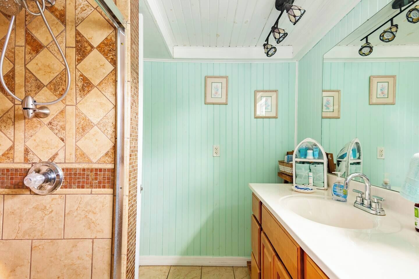 A bathroom with a shower, a sink, and a mirror.