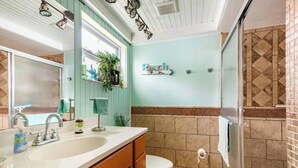 A bathroom with a large sink, a toilet, and a shower area. - Private bedroom and private bath at separate end of home with water views. (New Port Richey)