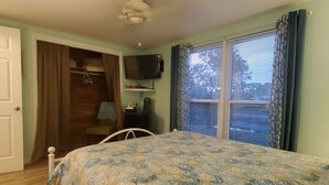 A bedroom with a bed, a ceiling fan, a TV, a window with blinds, and a closet with hanging clothes. - Private bedroom and private bath at separate end of home with water views. (New Port Richey)