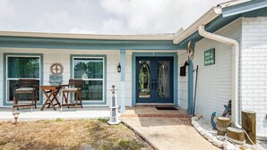 A house with a blue door, a front porch with two chairs, and a sign for 'Anna's Mobile Veterinary Services'. - Private bedroom and private bath at separate end of home with water views. (New Port Richey)