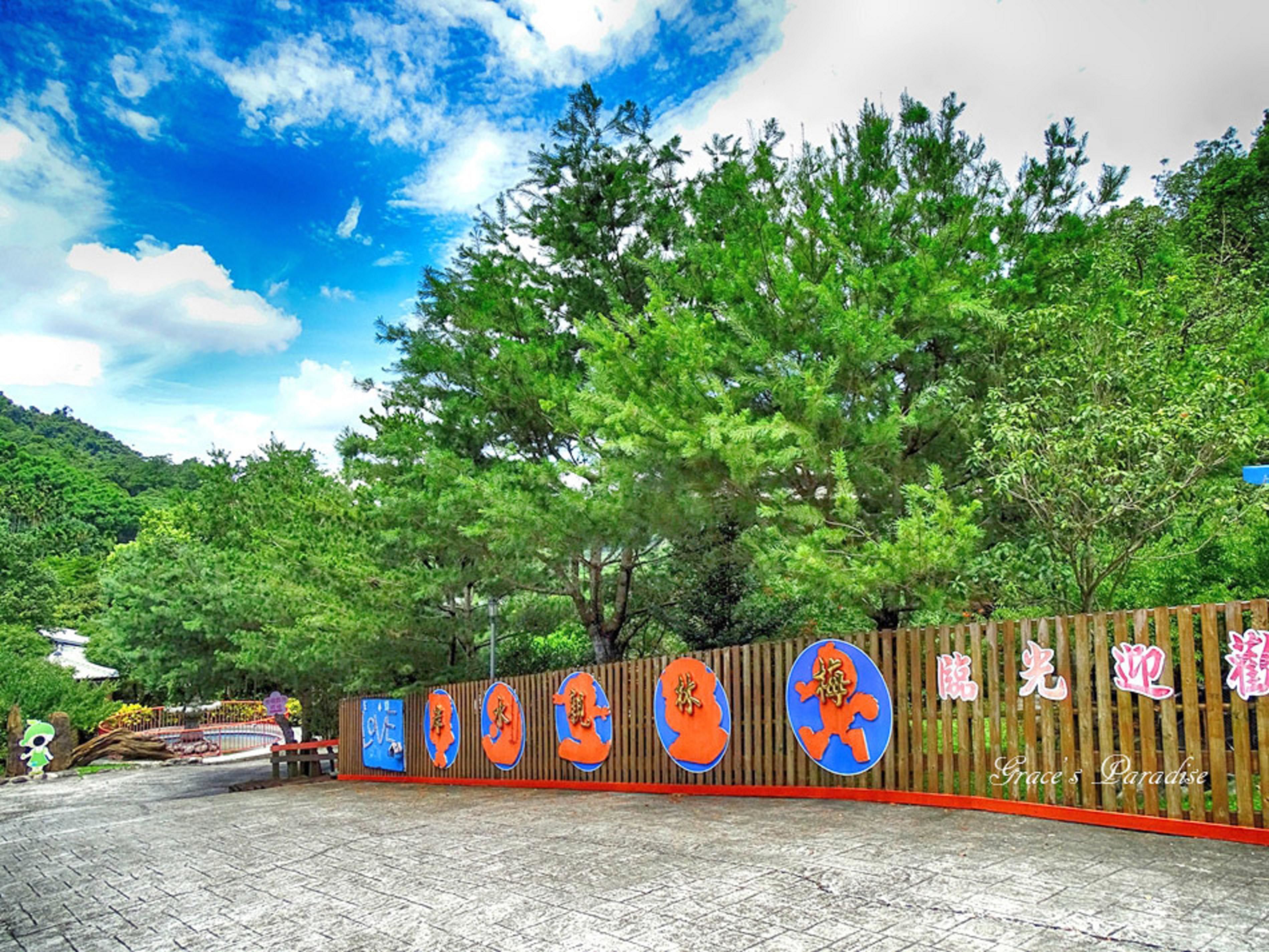A paved entrance area with a wooden fence and colorful circular signs.