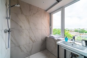 Estudio de diseñador, varias camas, vista a la ciudad | Regadera en el baño