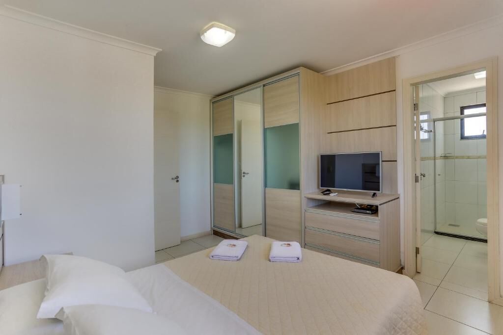 A hotel room with a bed, a TV, a wardrobe, and a bathroom visible through an open door.