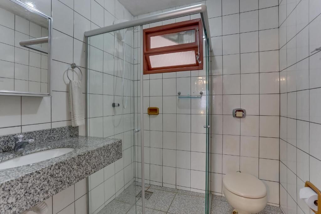 A bathroom with a glass shower enclosure, a granite countertop sink, and a toilet.