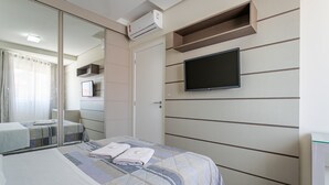 Hotellihuone, jossa on sänky, seinälle asennettu televisio ja liukuovi, joka johtaa kylpyhuoneeseen.