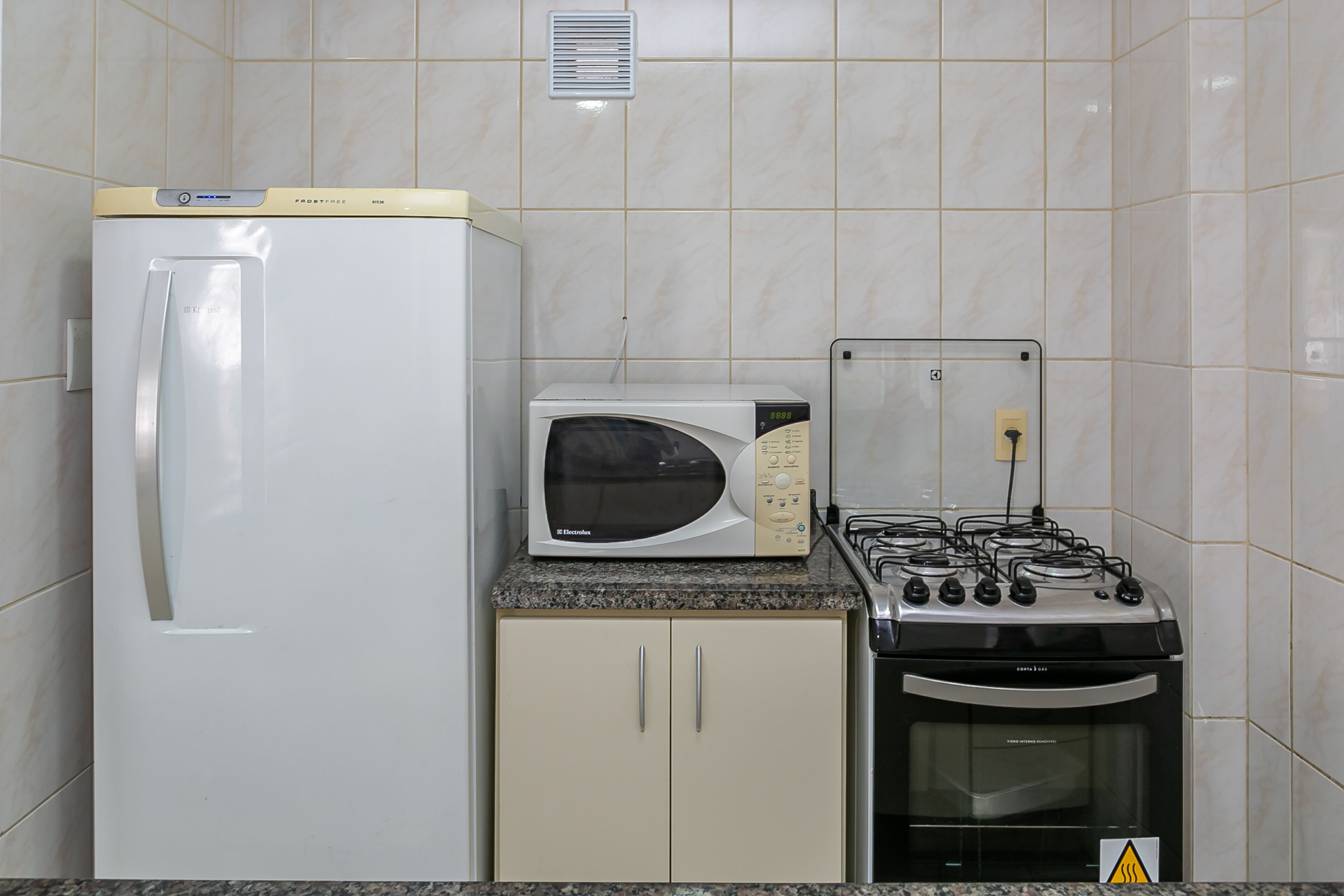 Cocina compacta equipada con refrigerador, microondas, estufa y horno.