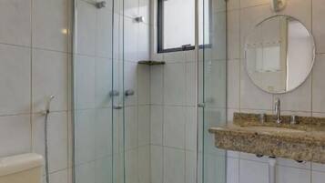 A modern bathroom with a glass-enclosed shower, a toilet, and a sink with a granite countertop.