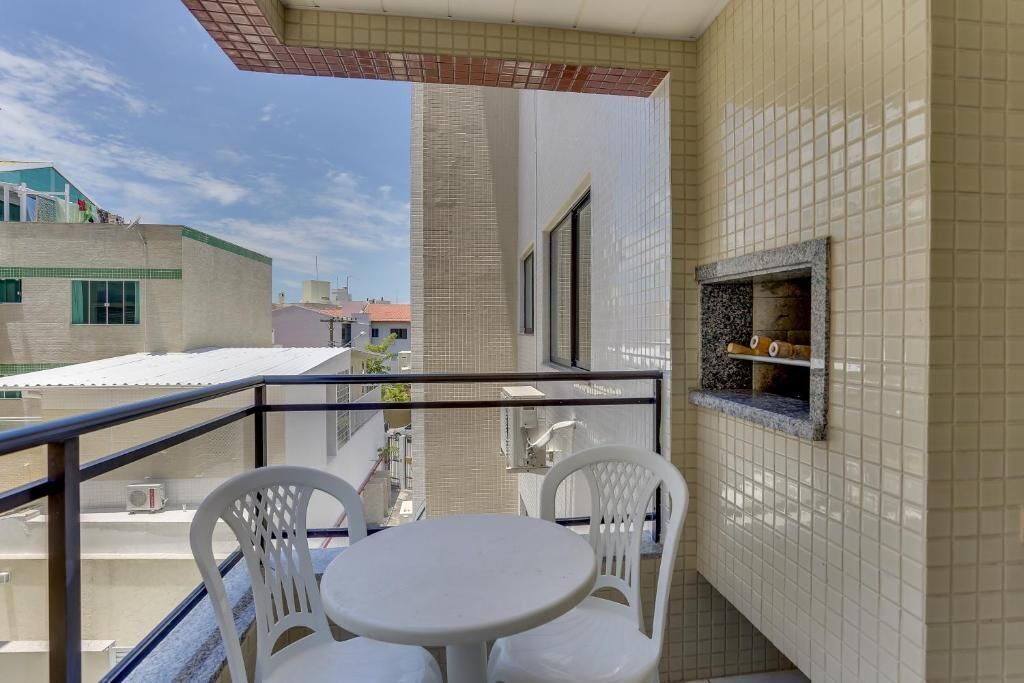 A balcony with a white table and chairs, a tiled wall, and a small stone fireplace.