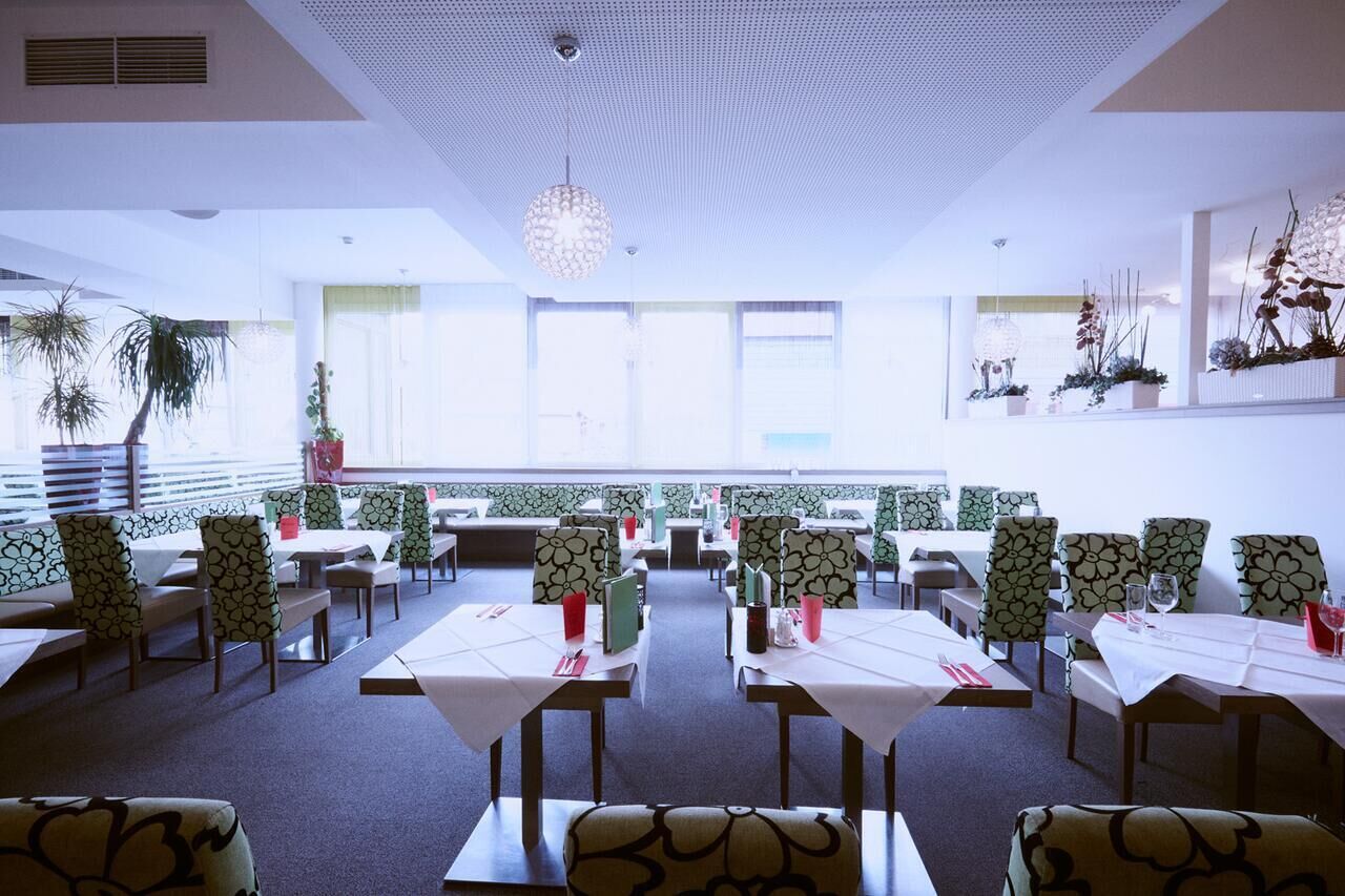 Un restaurante con una decoración moderna, que incluye una combinación de asientos tipo banca y mesas, sillas estampadas y un techo decorativo.
