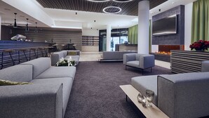 A modern lobby with grey sofas, a coffee table, and a TV mounted on the wall. - Hotel Planai by Alpeffect Hotels (Schladming)