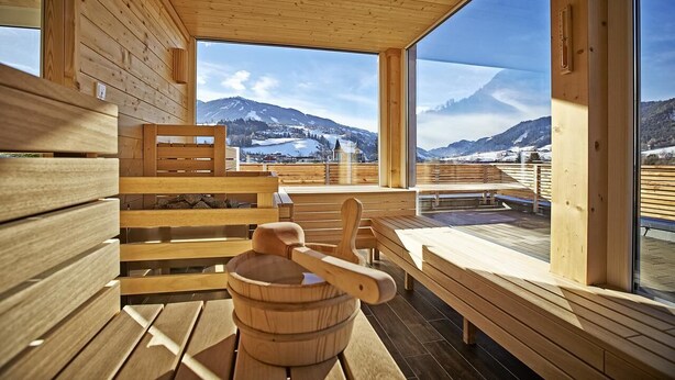 A wooden cabin with large windows offering a view of snow-covered mountains. - Hotel Planai by Alpeffect Hotels (Schladming)