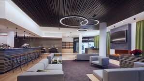 A modern lobby with a bar area, seating, and a large TV screen. - Hotel Planai by Alpeffect Hotels (Schladming)