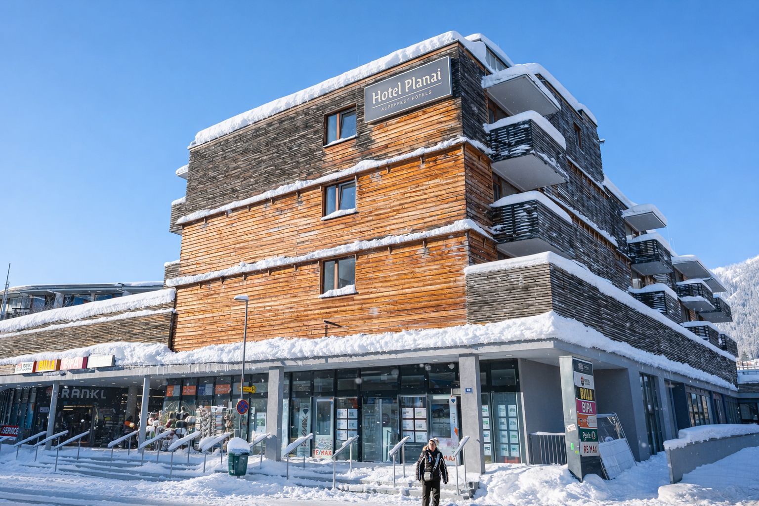 A multi-story hotel with a wooden facade and balconies, surrounded by snow.