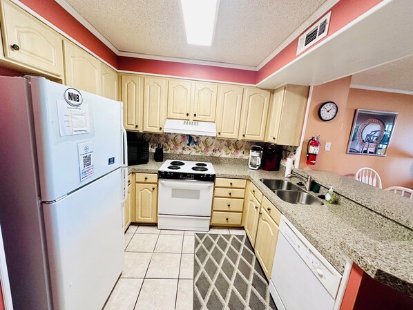 A compact kitchen with a refrigerator, microwave, stove, and sink. - Experience Tilghman Beach and Racquet Club Unit 122! Oceanfront, Pools, Tennis, Close to Main Street! (North Myrtle Beach)