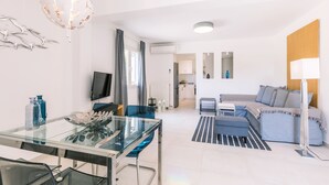 A modern living room with a glass dining table, a sofa, and a TV. - Seaview Luxurious Apartment near Corfu Town - Adults Only By Konnect (Corfu)