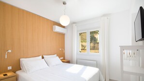 A modern bedroom with a wooden headboard, a large bed with white bedding, a bedside table with a phone, and a window with curtains. - Seaview Luxurious Apartment near Corfu Town - Adults Only By Konnect (Corfu)