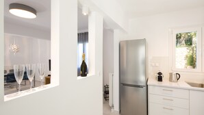 A modern kitchen with a stainless steel refrigerator, white cabinetry, and a window with a view of greenery. - Seaview Luxurious Apartment near Corfu Town - Adults Only By Konnect (Corfu)