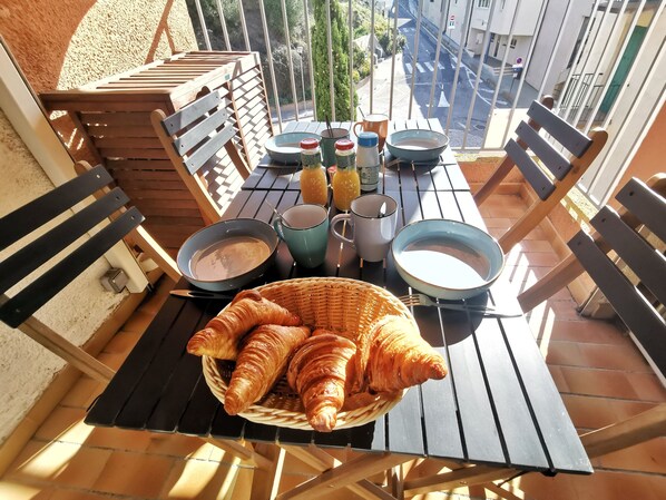 Een ontbijttafel met croissants, een mand en diverse ontbijtartikelen.