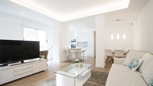 A modern living room with a flat-screen TV, a glass coffee table, a sofa, and a dining area with chairs and a table. - Spacious 4BR Apartment, Walk to Beach (Alacant)